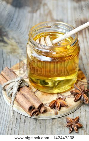 Golden honey with honeystick. cinnamon and anise stars on wooden table