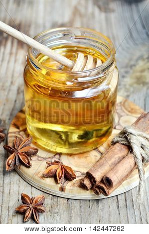 Golden honey with honeystick. cinnamon and anise stars on wooden table
