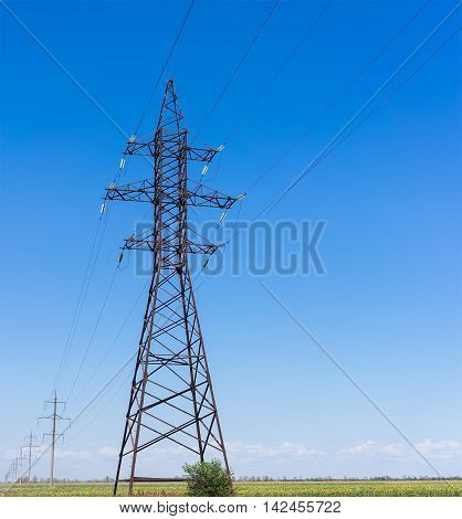 Electricity pylon silhouette against blue sky background. High voltage tower.