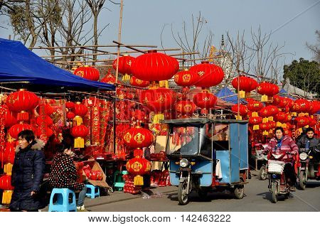 Pengzhou China - January 21 2014: Bright red lanterns and other Chinese New Year decorations sold by vendors line the street in the Long Xing outdoor marketplace