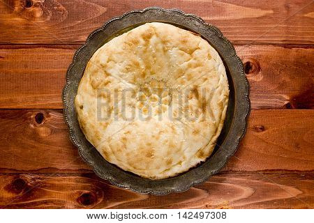 Traditional Uzbek bread on a plate on a wooden background