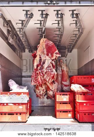 Raw beef butchery. Transport scene of raw meat, hanging in a truck.