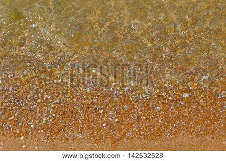 Wave Transparent Sea Water over Sand beach with Small Pebbles Top View background