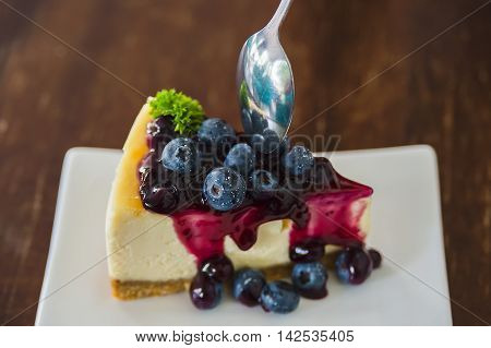 Blueberry cheesecake on white dish with spoon