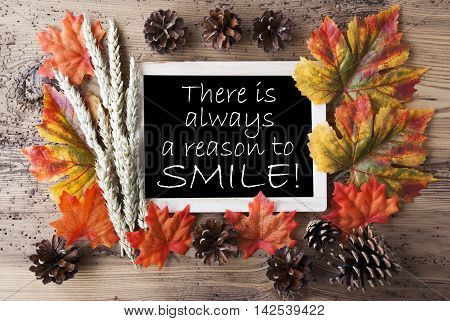 Blackboard With Autumn Or Fall Decoration. Greeting Card For Seasons Greetings. Colorful Leaves, Fir Cone And Barley On Aged Wooden Background. English Quote There Is Always A Reason To Smile