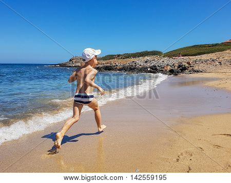 Boy resting and runs along the beach. Children's summer holiday by the sea