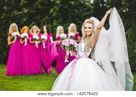Bride with bridesmaids in a park on the wedding day