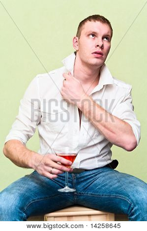 Pohledný muž sedí s sklenka alkoholu