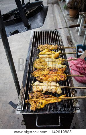 Grilling chicken plugged with bamboo on the tray