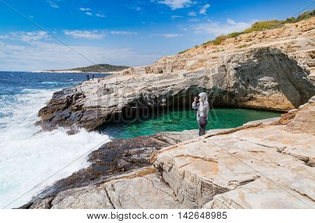 Thassos, Greece - May 2, 2016: Man taking photo near Giola natural sea water pool located on Thassos island, Greece