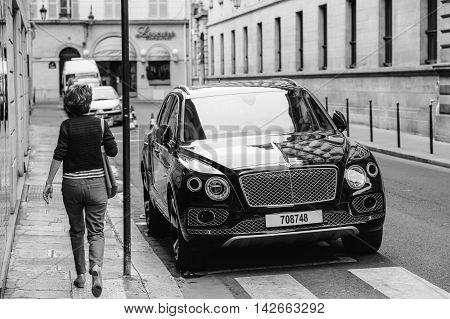 PARIS FRANCE - MAY 21 2016: Woman admiring the luxury Bentley Bentayga Hybrid SUV on the streets of Paris France