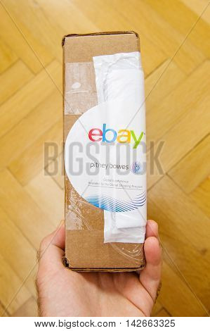 PARIS FRANCE - JUN 8 2016: Man hoding Ebay and Pitney Bowens box logotype printed on cardboard box security scotch tape of International Shipping Program.