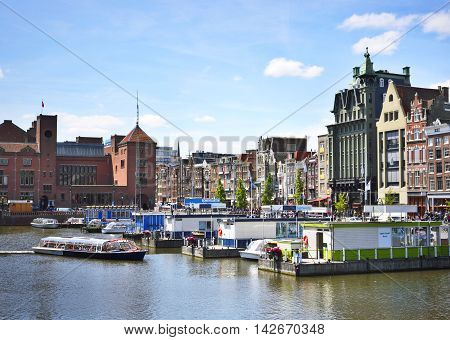 Cityscape of Amsterdam, the Netherlands, with tour boats and church tower.