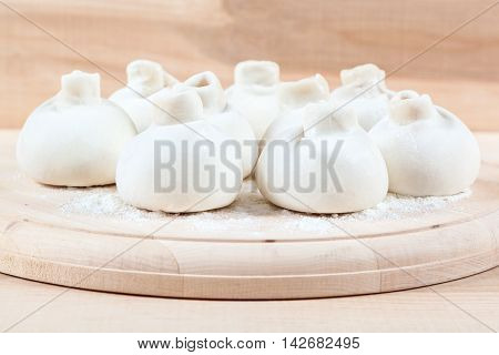 Manti dumplings on the a wooden board.