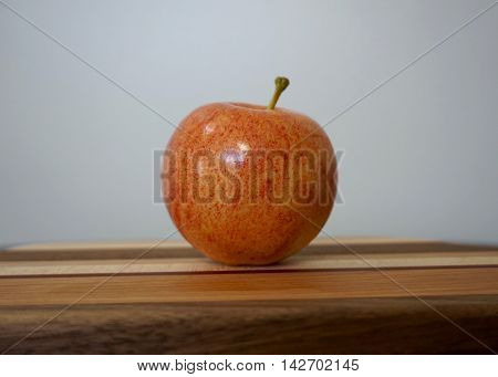 Solitary red apple on patterned cutting board