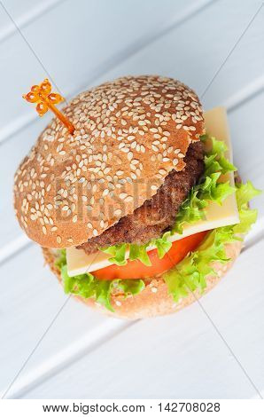 Hamburger with salad cheese tomato meat on white backdrop. Popular snack.