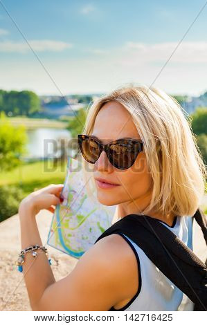 Female traveler stands and looking at map of the city on the background of modern residential quarter of Krakow and Vistula River. Wawel castle. Poland.