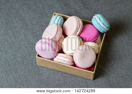 Multi-colored macaron from polymer clay in a box on the background of gray fabric