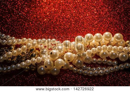 Close up of beautiful creamy and golden pearls against a red glitter. Luxury jewelry background