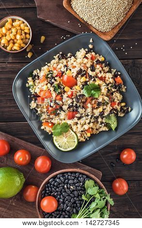 Black bean quinoa salad on rustic wooden background top view. Toned