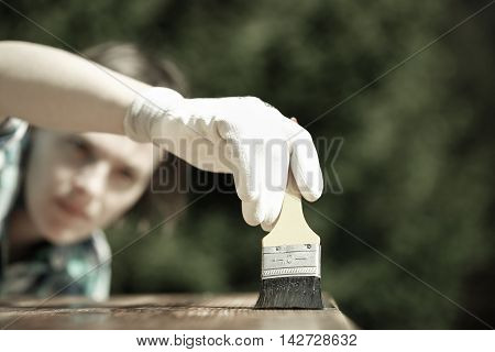 Woman carpenter inspecting her work after treating wood with protection paint. Outdoor protection carpentry hard at work quality control home improvement do-it-yourself concept.