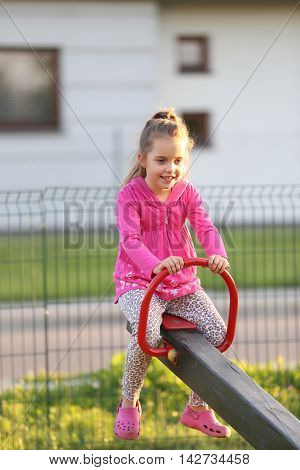 little girl wearing pink shirt lauging and playing at a playground