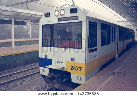 Northern Spain - June 19 2010: Passenger train stands at the station at foggy morning time. This railway connects Hendaye France and Ferrol northwest Spain has meter gauge track.