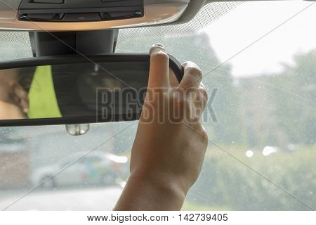 the girl in the car with beautiful manicure adjusts the rear view mirror