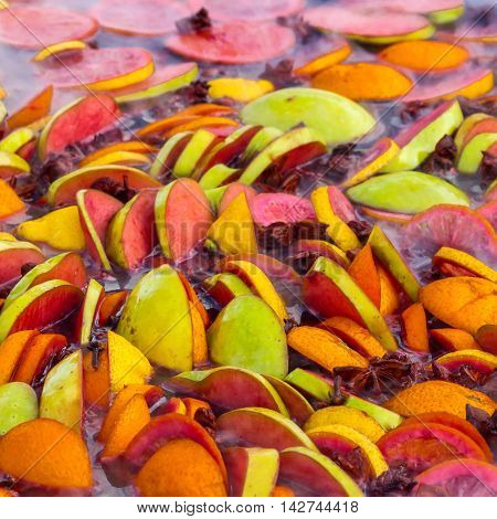 Cooking fruits and spices mulled wine in a large bowl