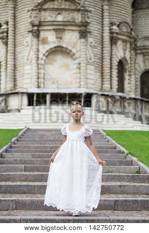 Portrait of a beautiful young little girl in white gown, summer outdoors