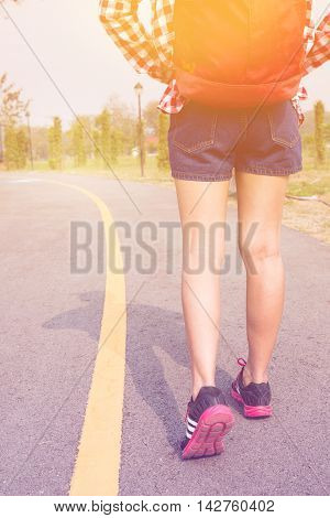Woman runner athlete feet running on the road with backpack in pastel or vintage style color