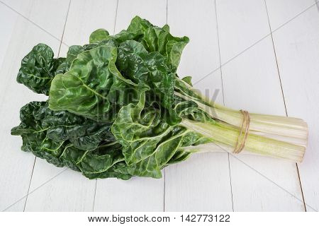 fresh green silverbeet leaves vegetable on white wooden background