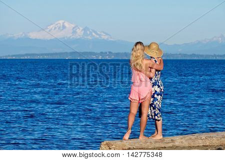 Mother and daughter on beach by blue sea. Centennial Beach at Boundary Bay Regional Park Tsawwassen British Columbia Canada.