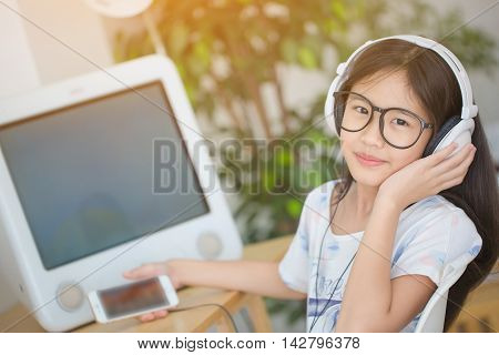 Attractive Asian girl listening music on smartphone with headphone in the room