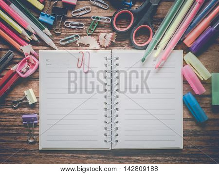 Top view notebook and office suplies on wood table made vintage-retro style