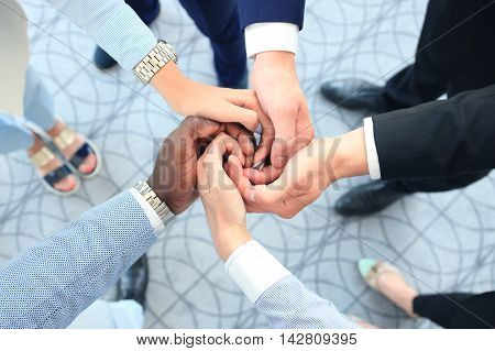 Multiethnic group of young people putting their hands on top of each other. Close up image of young business people making a stack of hands.