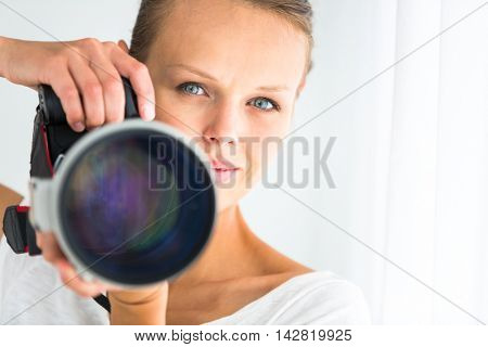 Pretty, female photographer with digital camera - DSLR and a huge telephoto lens (color toned image; shallow DOF)