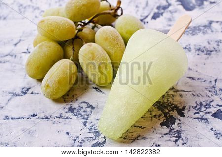 Ice lolly of green grapes on concrete background. Selective focus.