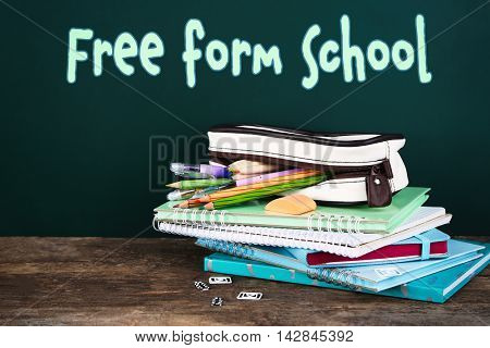 Home learning concept. Pencil case with various stationery on table, on blackboard background