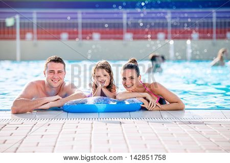 Mother, Father And Daughter In Swimming Pool. Sunny Summer.