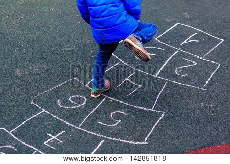 kid playing hopscotch on playground outdoors, children outdoor activities