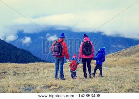 family with little son and daughter hiking in winter mountains