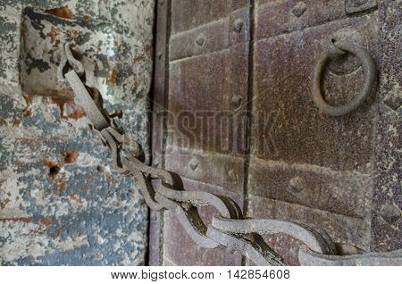 Old rusty chain and massive wrought iron doors