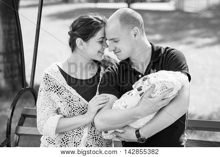 Happy Family Resting In A Park. Father Holding Newborn Daughter In Her Arms.black And White Photogra