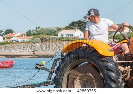 Men Getting Boats Out Of Water With Tractors On The Beach
