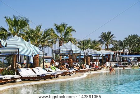 people relax by the pool with sun loungers parasols and palm trees in the resort. Egypt. Sharm el Sheikh. September 2011