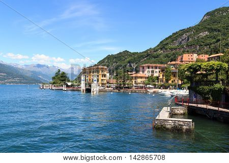 Varenna, Italy - June 20, 2016: Ferry dock in village Varenna at Lake Como with mountains in Lombardy. The Ferries are linking Varenna to Bellagio and Menaggio. Varenna is a picturesque town and famous for its colorful houses.