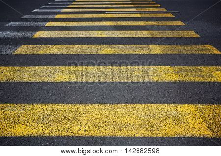 Yellow pedestrian crossing with white stripes on tarmac. Crosswalk on asphalt road. Safety marking.