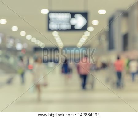 Blurred walking passengers with luggage in airport arrival terminal. Travel concept background in vintage filtered effect