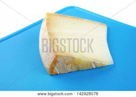 piece of light gauda cheese on blue board